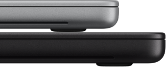 14 Zoll MacBook Pro mit PROLED XDR Display, Farbe Silber, liegt auf einem 16 Zoll  Modell in Space Schwarz, um den Größenunterschied zu verdeutlichen
